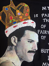 Close-up of hand-painted Freddie Mercury profile with crown and butterfly on black fabric, featuring poetic phrase 2