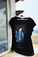 Hand-painted Mick Jagger T-shirt hanging by a gazebo with beach and sea in the background – bold artistic style in natural light