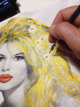 Artist’s hand painting Brigitte Bardot on T-shirt, with detailed brushwork and colors in progress.