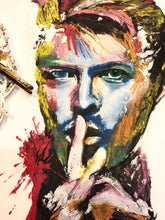 Close-up of David Bowie’s hand-painted face on white T-shirt with brush nearby – vibrant colors and 3D detail