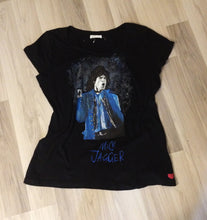 Full view of black T-shirt with hand-painted Mick Jagger portrait laid on wooden floor – striking art to wear