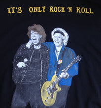 Close-up of Mick Jagger & Keef hand-painted on a black  t-shirt, wearing a silver-glitter black jacket and holding a microphone.