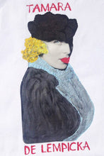 Close-up of a hand-painted portrait of Tamara de Lempicka on a t-shirt, showing detailed brushstrokes and her iconic Art Deco expression.