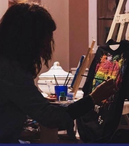 Artist painting a custom T-shirt on an easel – handmade wearable art in progress