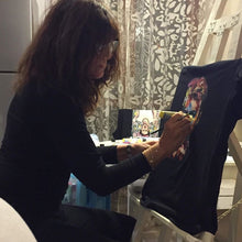 Female artist painting a custom T-shirt on an easel – handmade wearable art in progress