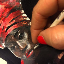 Artist’s hand painting the Black Queen portrait on black-T-shirt – brush in action, vivid colors forming