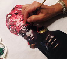 Artist’s hand painting the Black Queen portrait on white T-shirt – brush in action, vivid colors forming