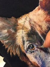 Close-up of artist’s hand painting a dog’s face on a custom T-shirt – detailed pet portrait in progress


